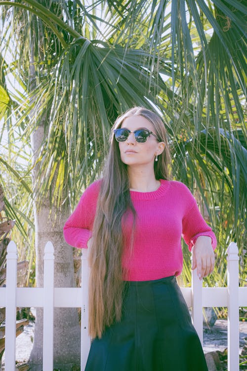 Young Woman in a Pink Sweater and a Black Skirt Posing Outdoors 