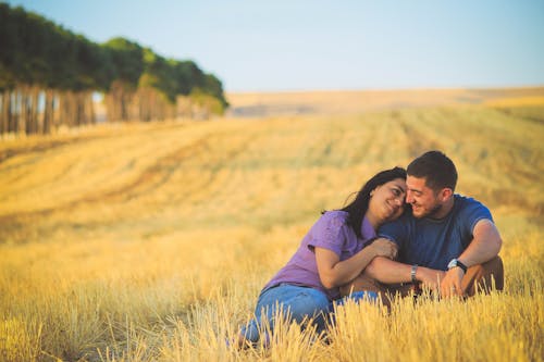 Man and Woman Sitting on Grass Field