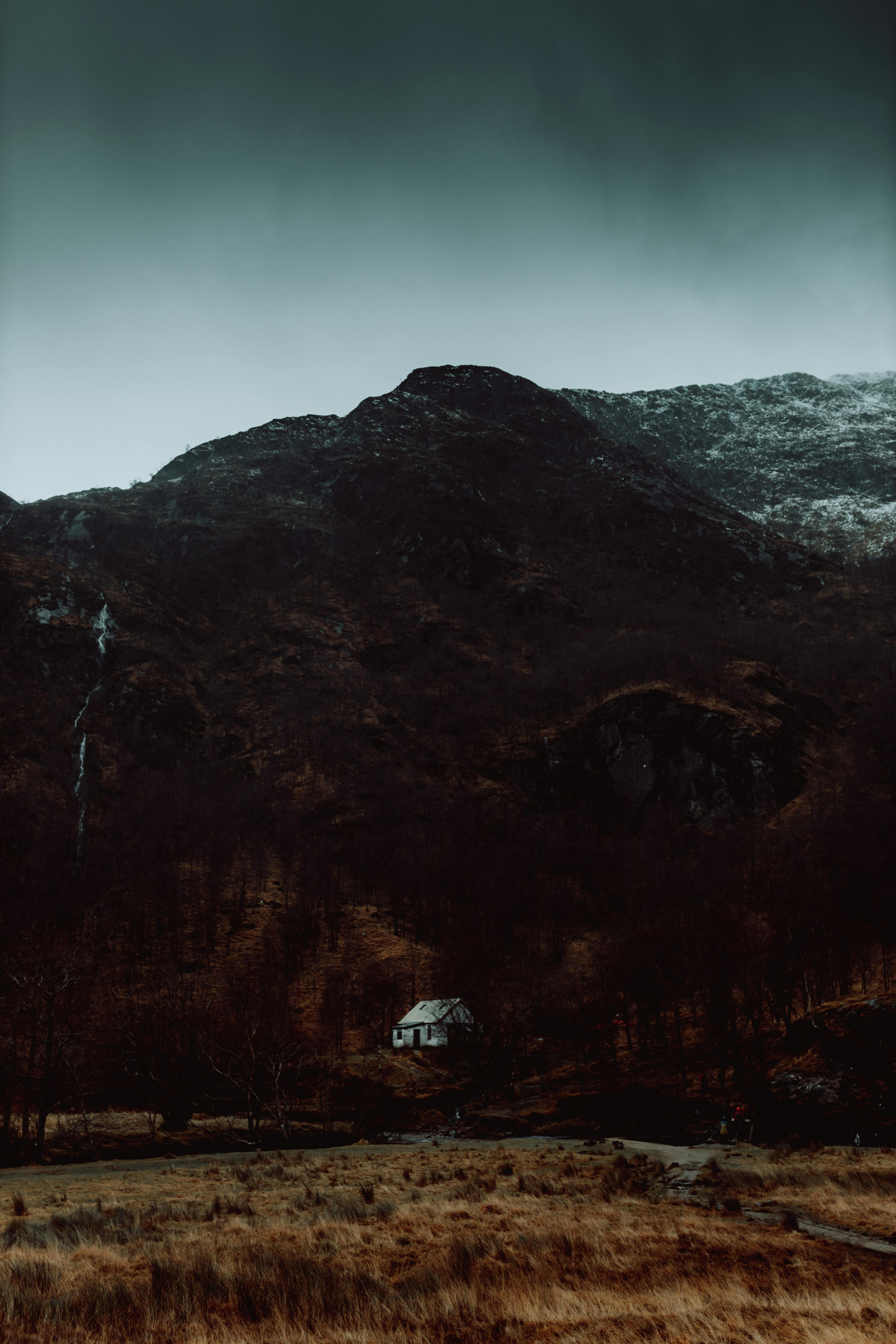 A secluded house under dark mountains, capturing the essence of fall's mystery.