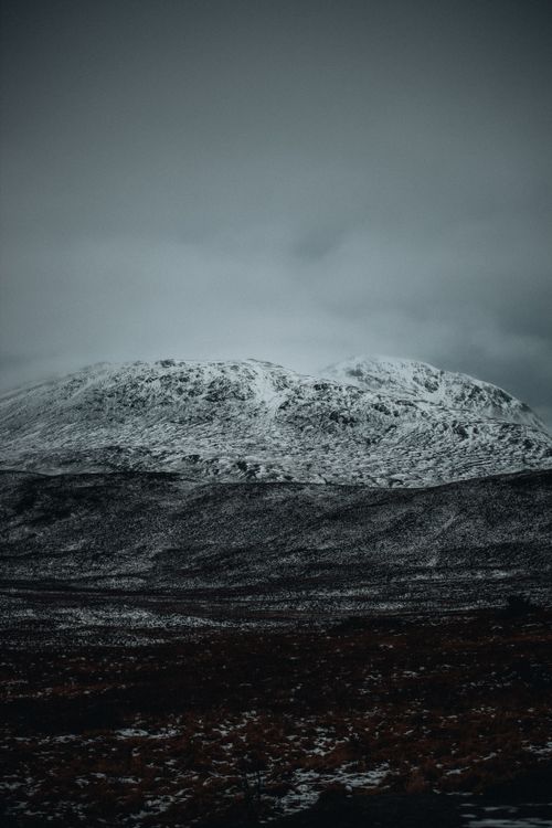 Free A dramatic landscape with a snow-covered mountain under overcast skies. Stock Photo