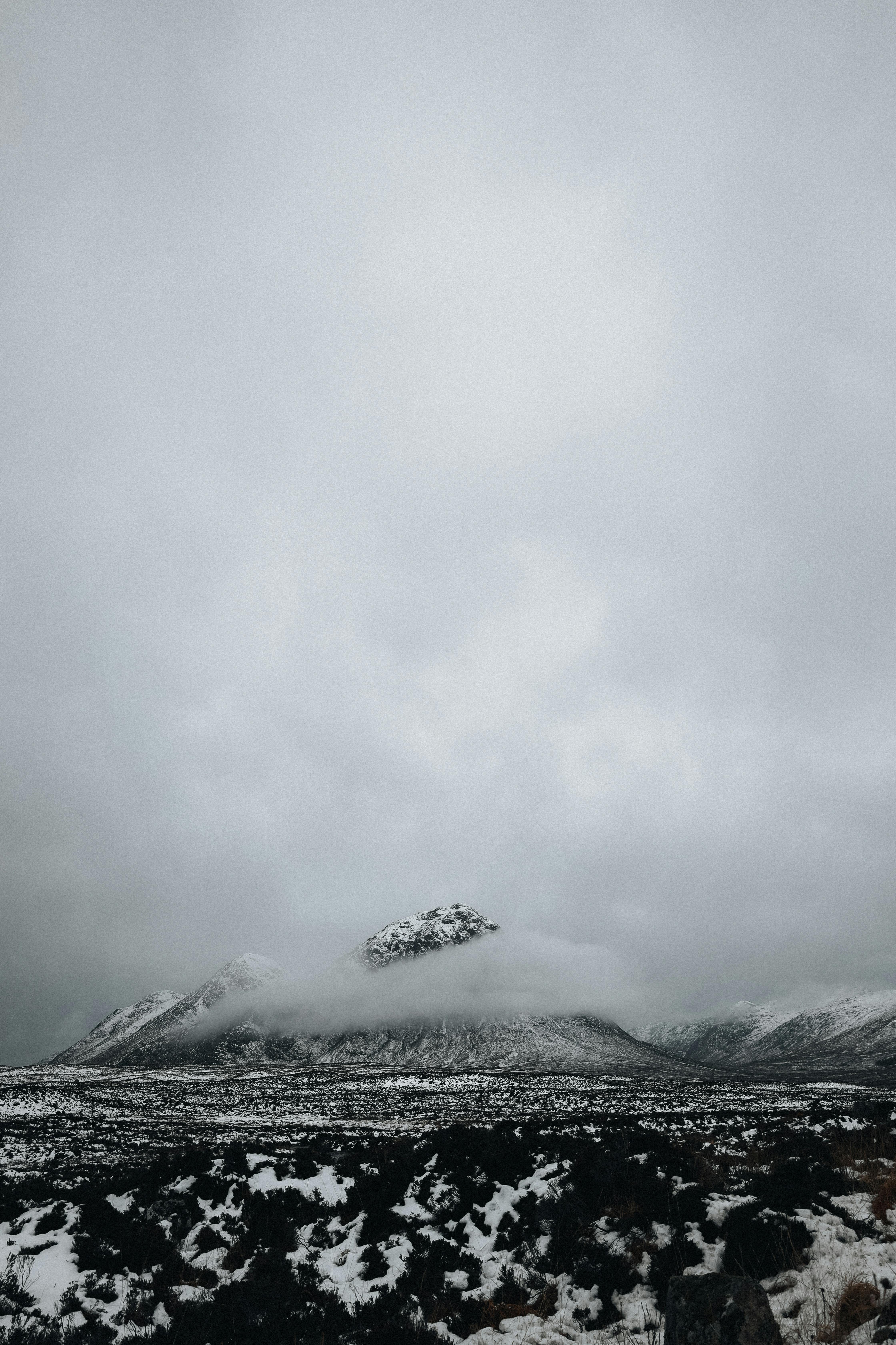 Gloomy winter landscape featuring a snow-covered mountain with foggy skies.