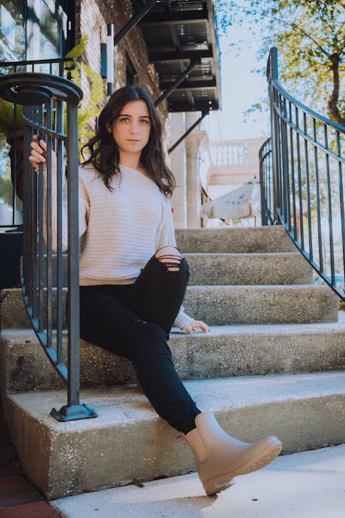 Young Brunette Sitting on Steps in front of a Building 