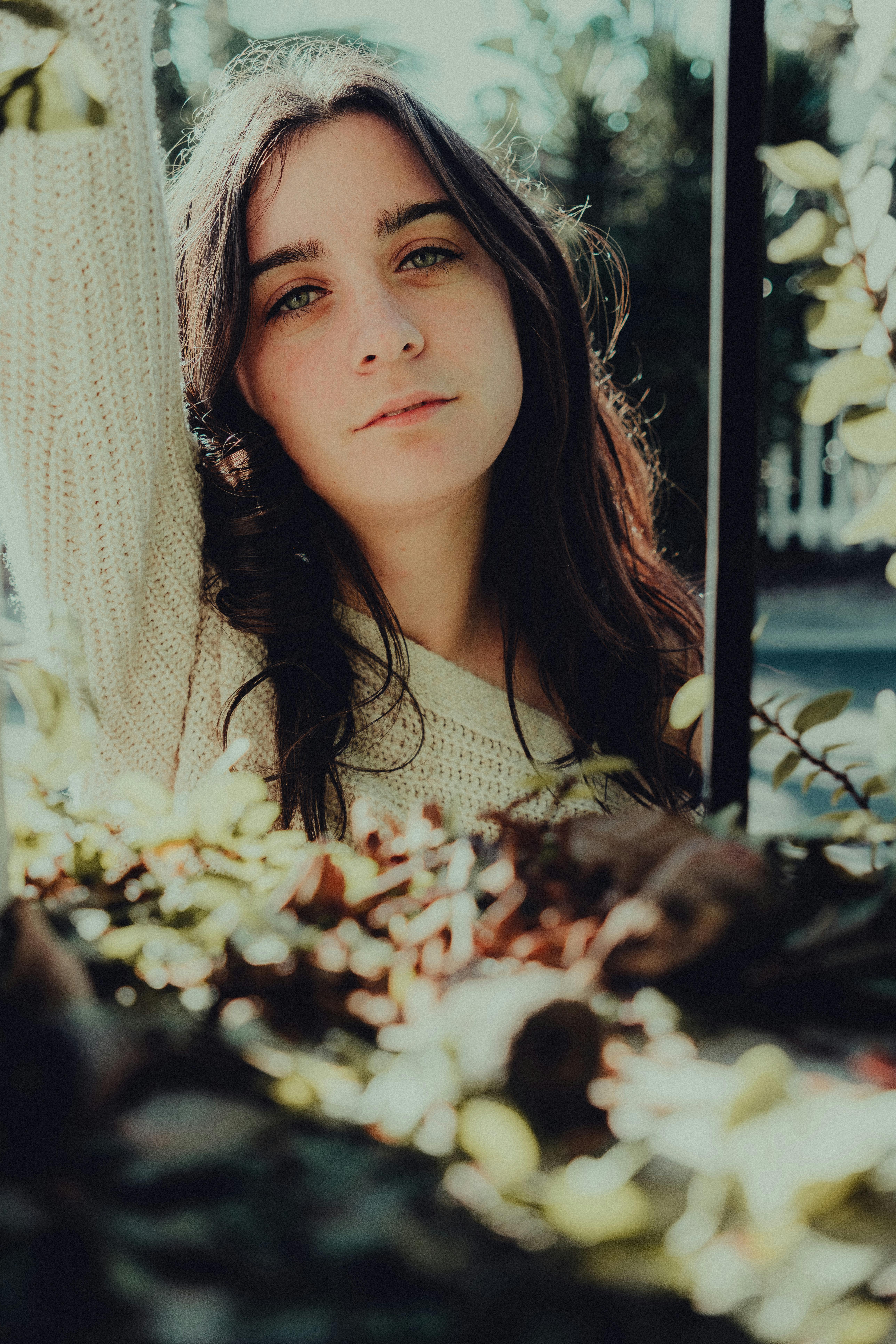 A natural portrait of a young woman outdoors, with sunlight highlighting her casual style.