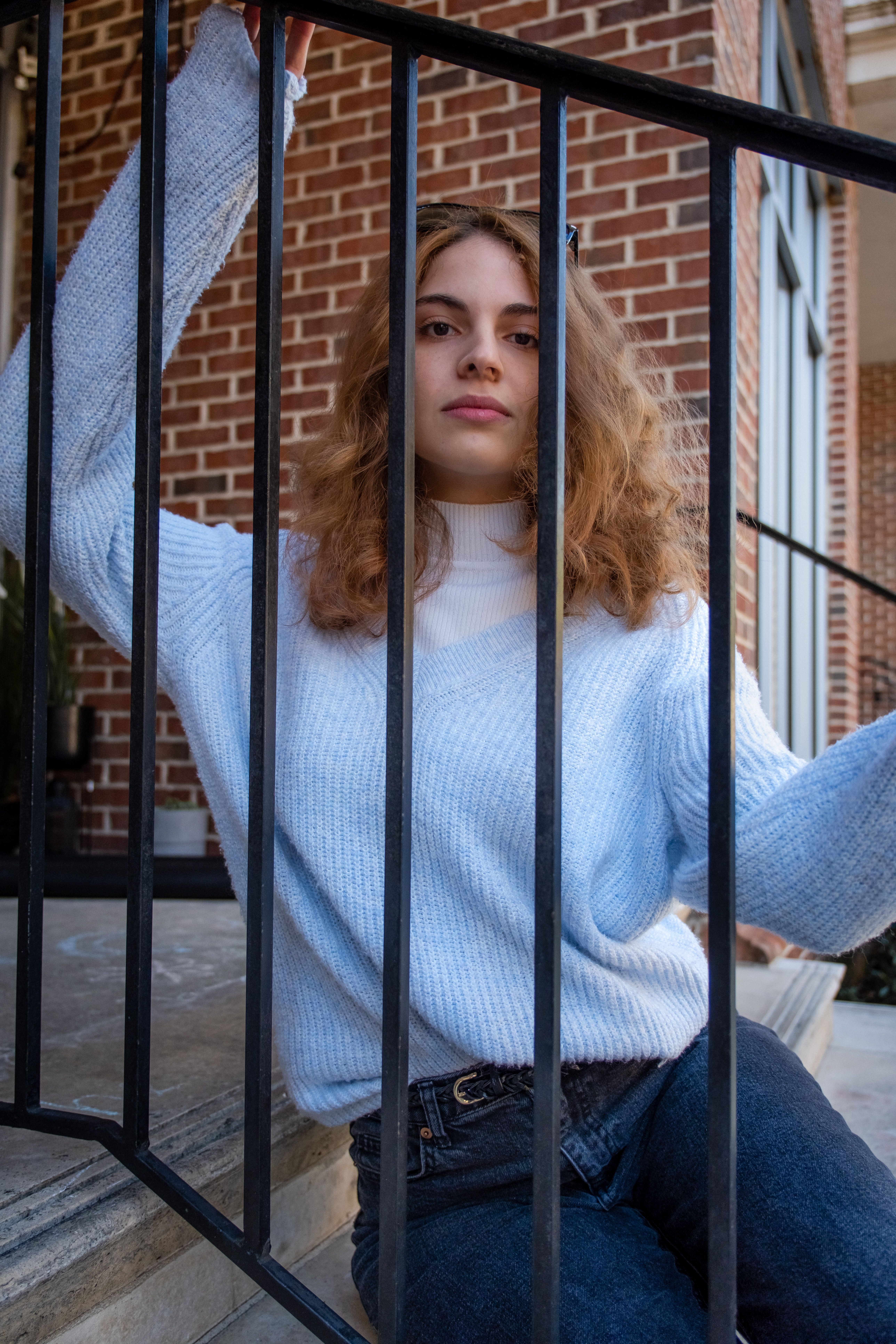 Young Woman in a Casual Outfit Sitting on Steps behind the Railing ...