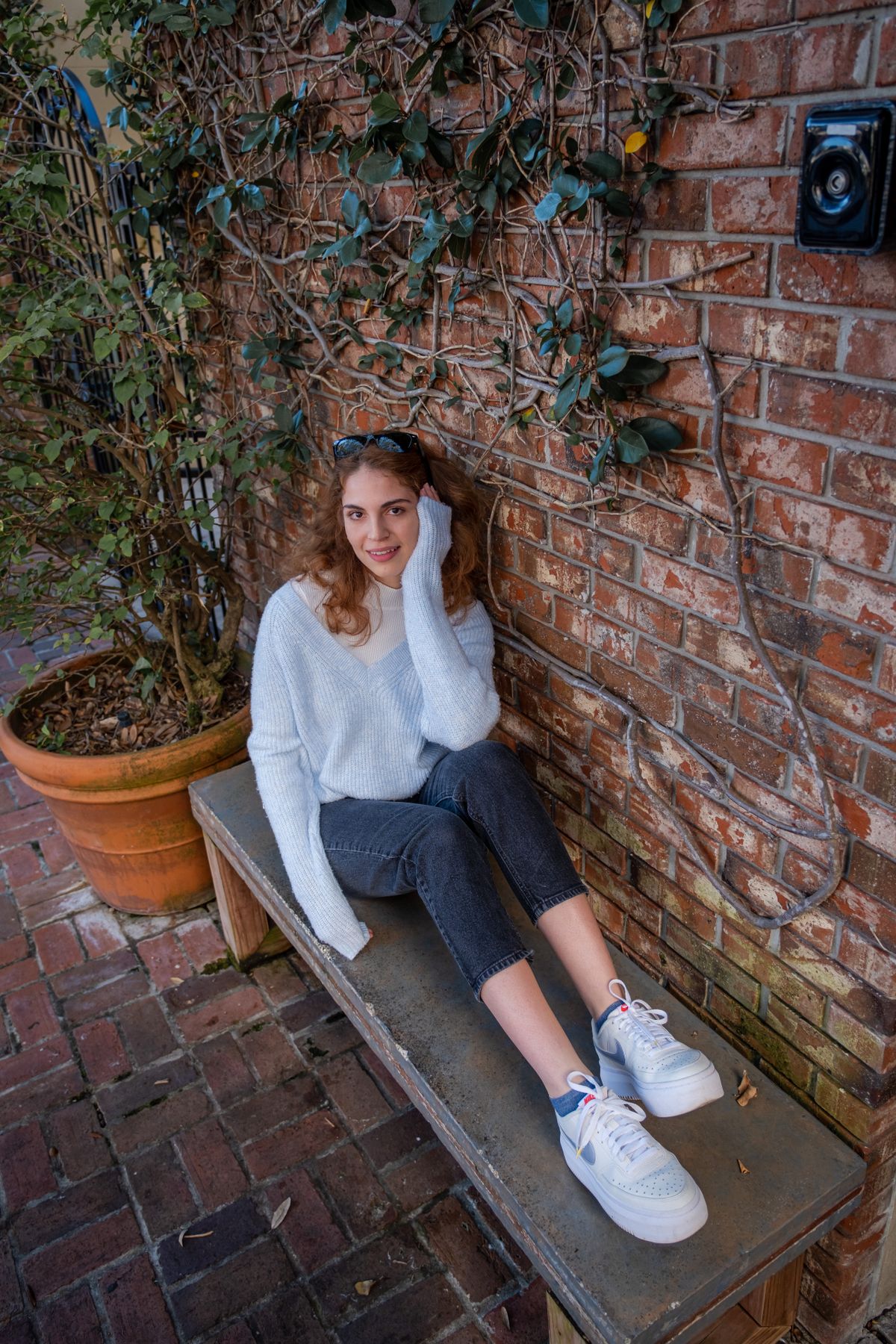 Cozy casual style with jeans and sweater by brick wall with ivy.