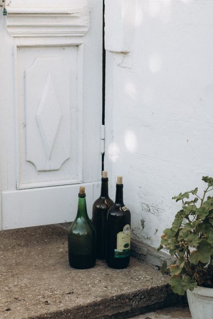 Three vintage bottles placed beside a rustic white door, creating a nostalgic outdoor scene.