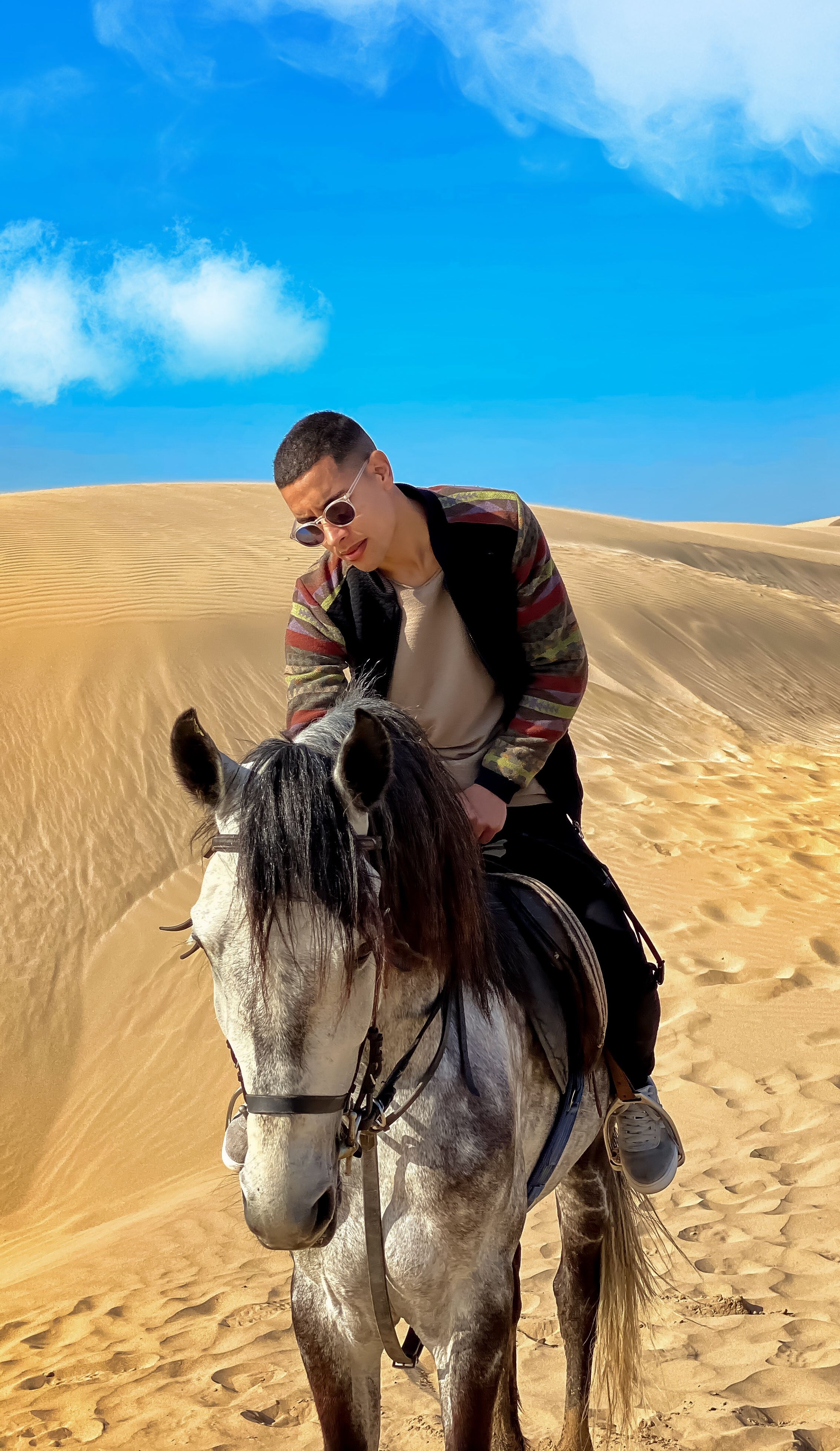 Young man on horseback navigating a serene desert under a clear blue sky.