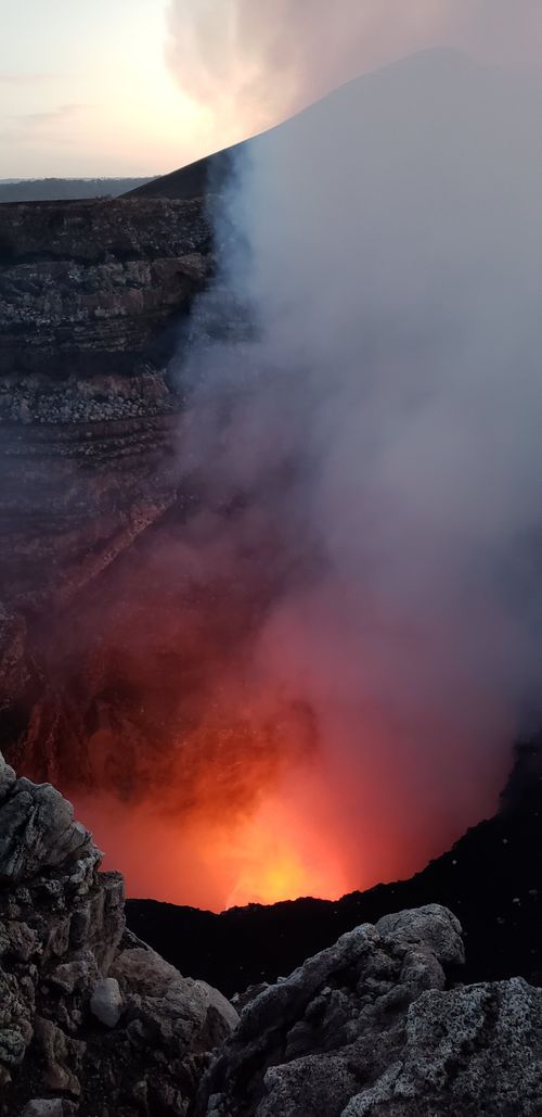 Free Vertical shot capturing smoke and glowing lava within a volcano crater at twilight. Stock Photo