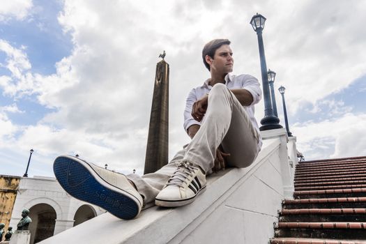 Man in casual attire posing by a landmark in Panama City, showcasing urban tourism.