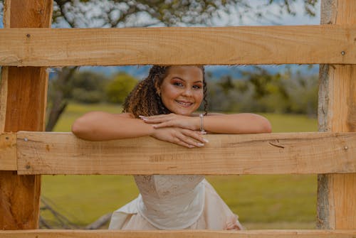 Photograph of a Girl Smiling Between Wood Planks