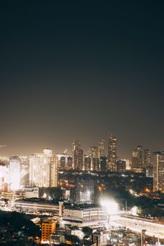 Aerial view of a city skyline illuminated at night, showcasing tall skyscrapers under a clear sky.