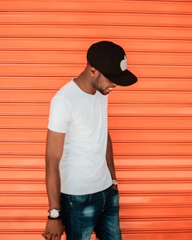 一名时尚男子在橙色背景下摆姿势，展现都市时尚