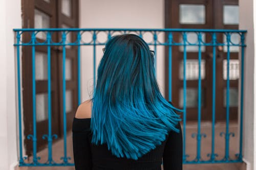 Mujer De Pelo Azul Frente A Valla Metálica