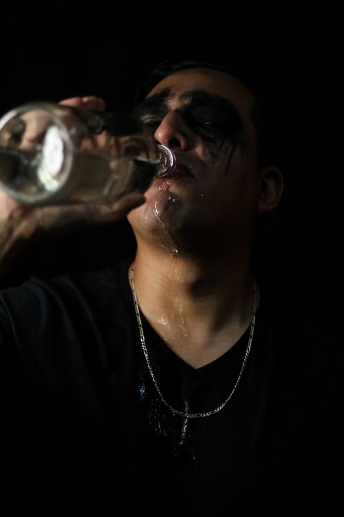 Free Artistic portrait of a man drinking from a bottle with dramatic lighting. Stock Photo