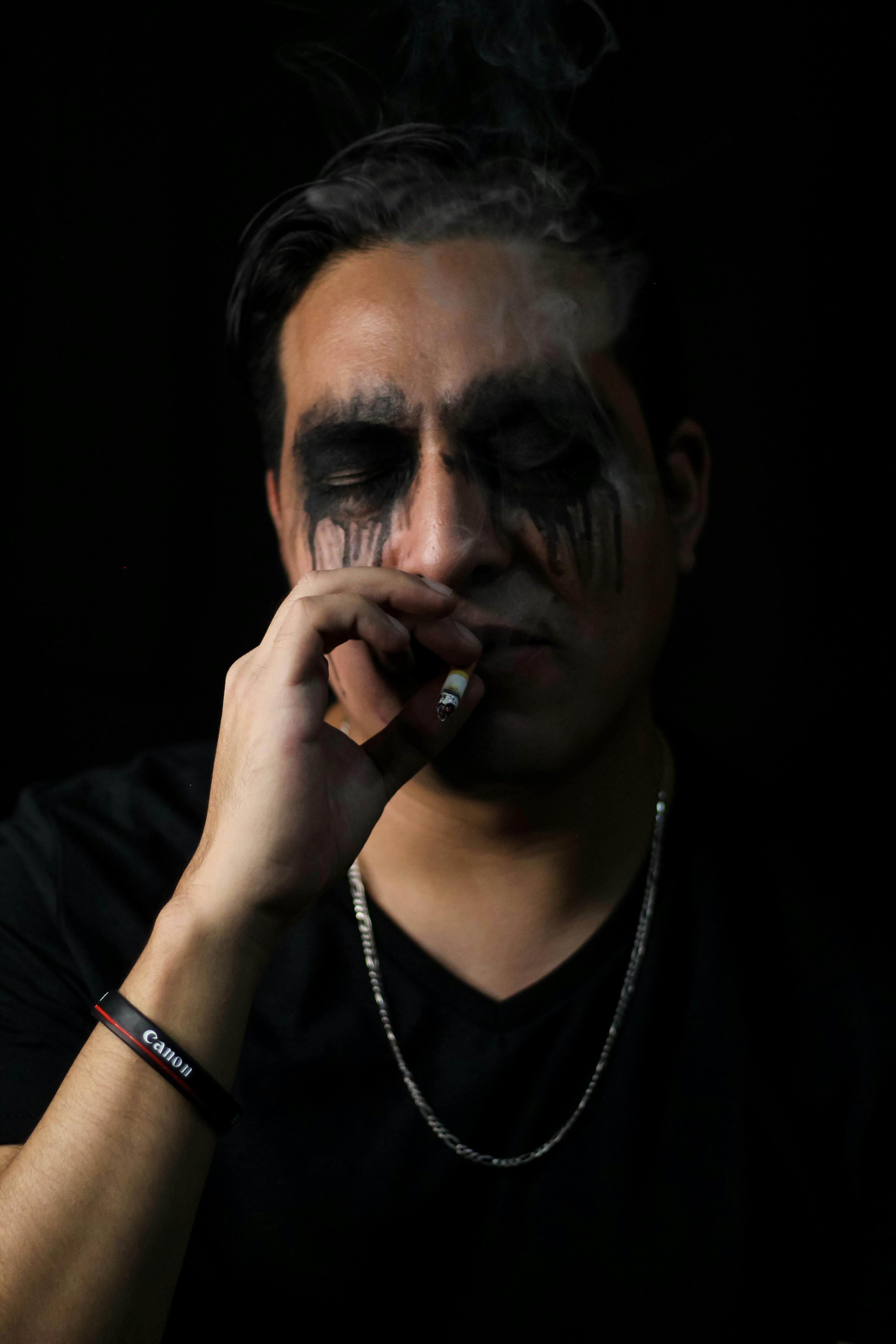 a man with black makeup and a cigarette