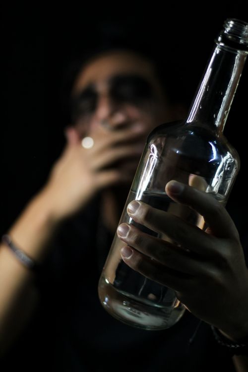 Free An artistic photo highlighting a man with a bottle, focused on reflection and mood. Stock Photo