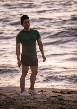 Man in green shirt and black shorts enjoying a sunset view on Puerto Vallarta beach, Mexico.