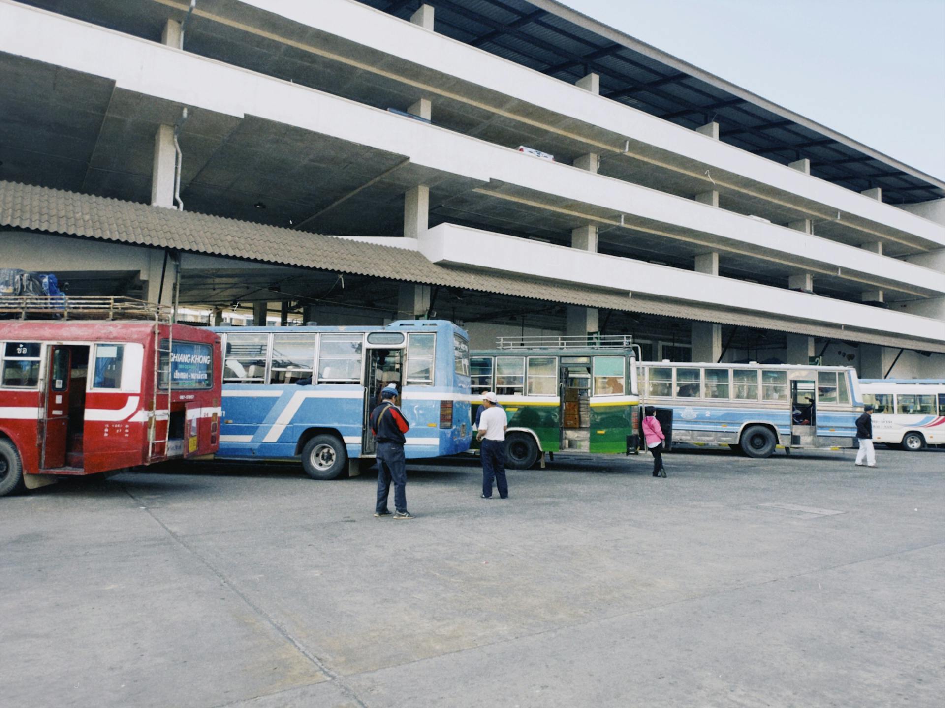 An urban bus station with several colorful buses parked, capturing public transportation in action.