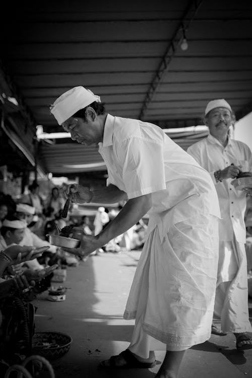 Man in White Gown Interacting with Sitting Crowd