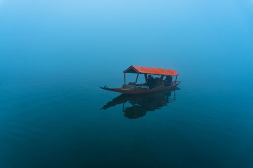 Free A peaceful boat journey through misty waters at dawn, reflecting tranquility. Stock Photo
