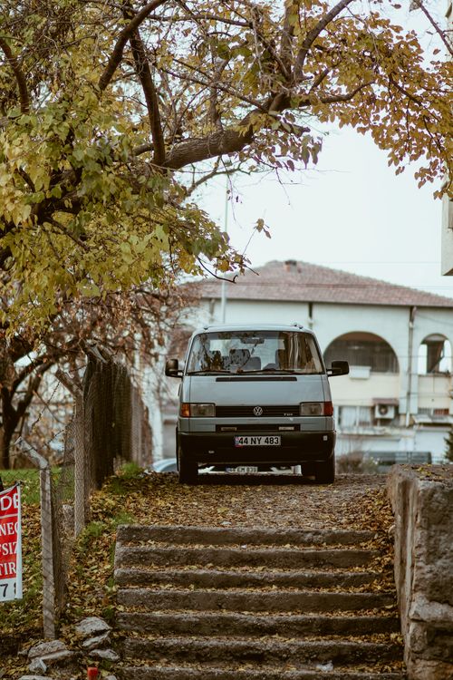 Free Classic van on a city street during autumn, surrounded by trees and steps. Stock Photo