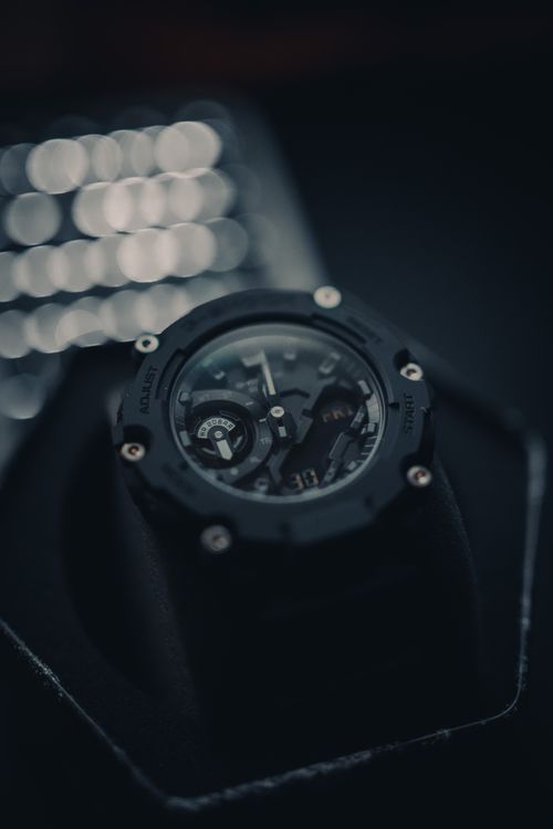 Free High-contrast close-up of a black wristwatch featuring intricate details against a blurred bokeh background. Stock Photo