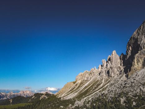 A breathtaking view of the Dolomites mountains under a clear blue sky, showcasing rugged rock formations.