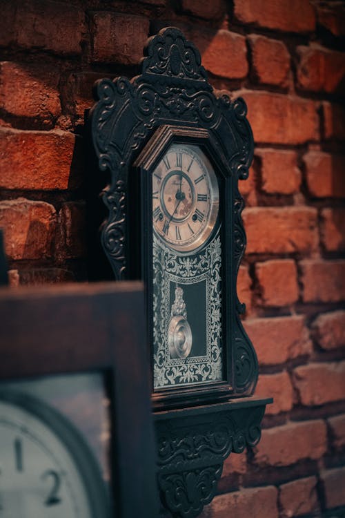 Antique Clock with a Pendulum Hanging on a Brick Wall