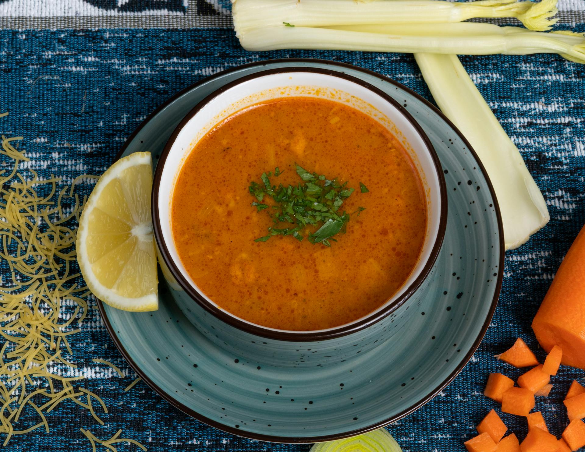 A bowl of soup with carrots, celery and lemon