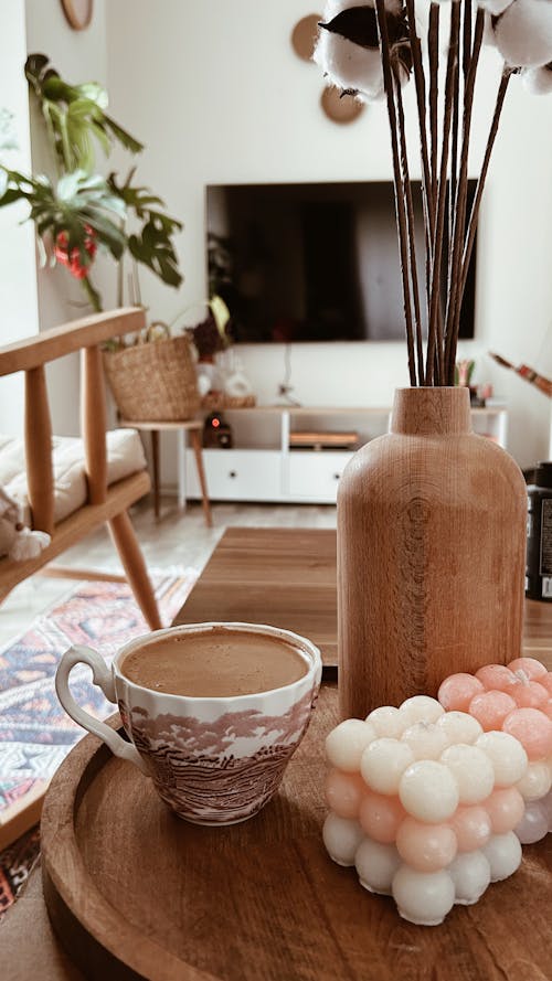 Cup of Coffee on a Table Next to Candles and a Wooden Vase