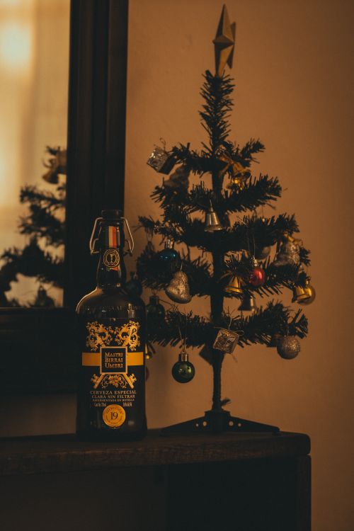 Free A cozy festive scene with a decorated Christmas tree and a bottle. Perfect for holiday themes. Stock Photo
