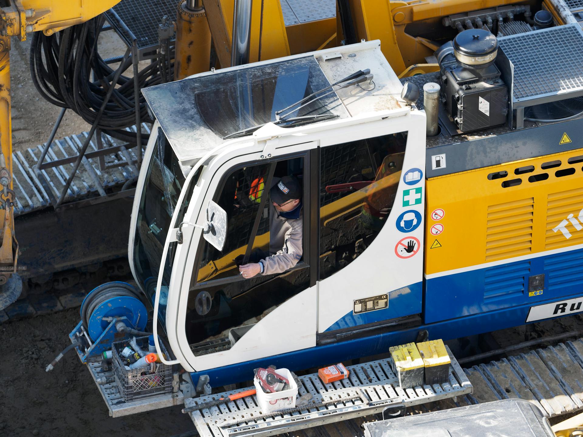 Aerial shot of an excavator operator working on a construction site with safety gear.