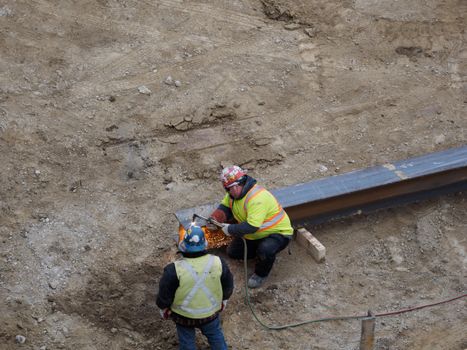 Two construction workers welding steel beams at a construction site.
