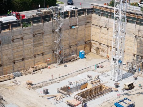 An aerial view of a construction site with workers and equipment under sunlight.