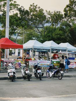 Diverse street food stalls with parked motorcycles in a vibrant market setting.