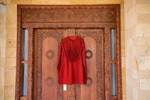 Red Clothes Hanging on Ornamented Door