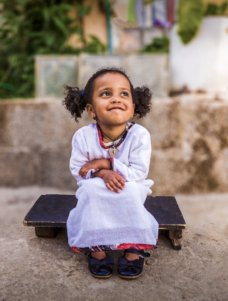 A Girl Sitting On A Wooden Chair