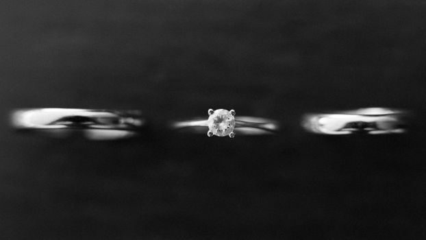 A black and white close-up of wedding and engagement rings, highlighting elegance.