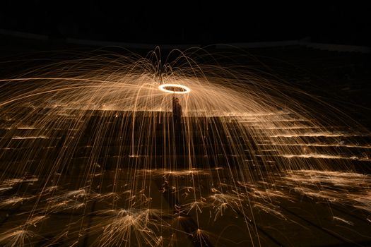 Captivating long exposure of steel wool spinning creating brilliant spark trails in night darkness.