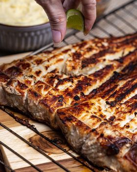 Close-up of grilled fish being prepared with lime for added flavor.