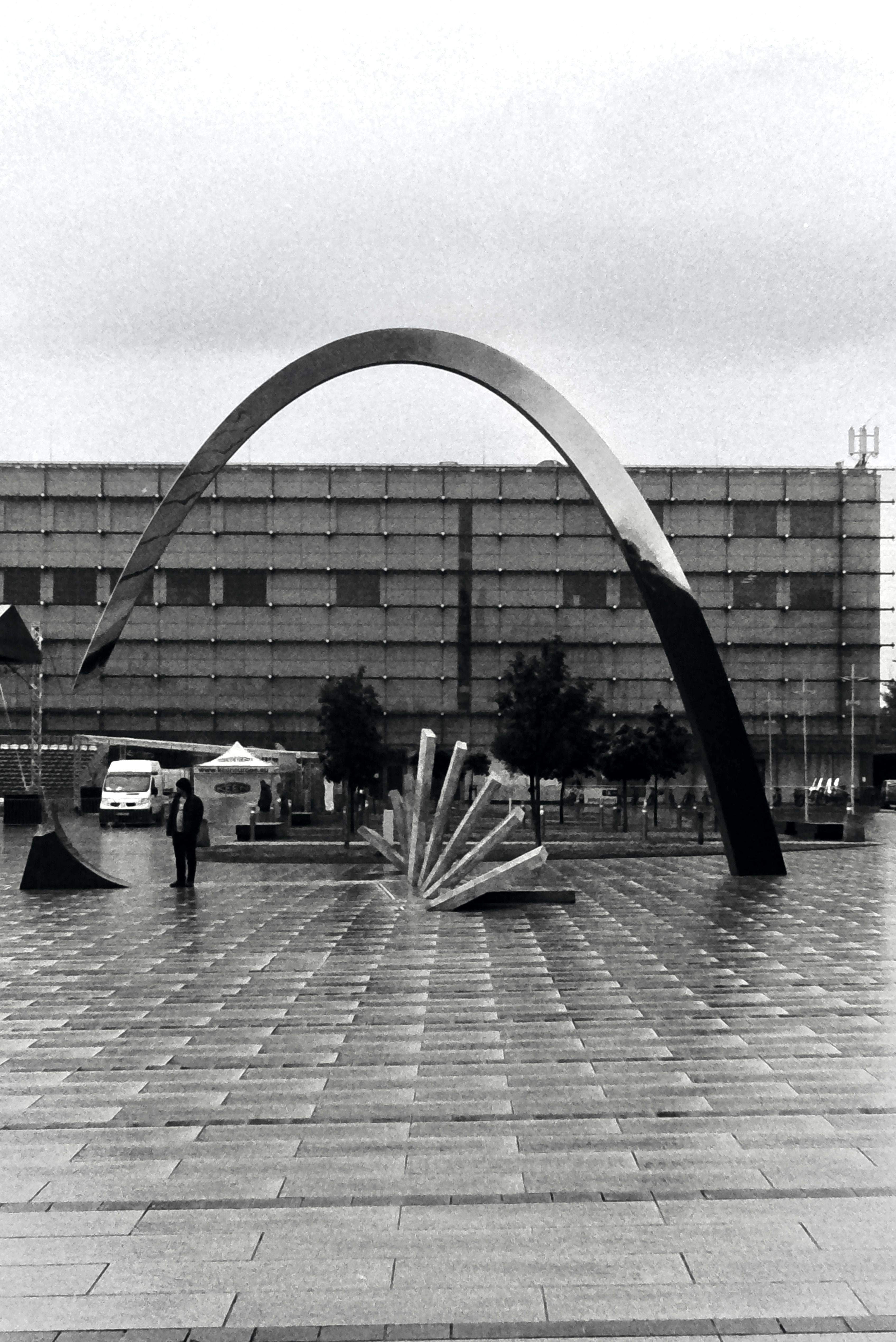 Black and white photo of Ryszard Kuklinski Monument in Kraków, highlighting urban architecture.