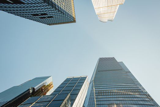 A low angle view showcases several modern skyscrapers reaching towards a clear sky, epitomizing urban architecture.