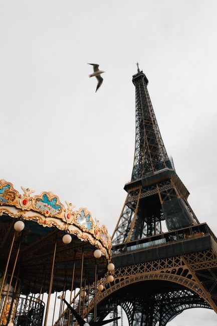 Stunning upward view of the Eiffel Tower with a classic carousel in Paris.