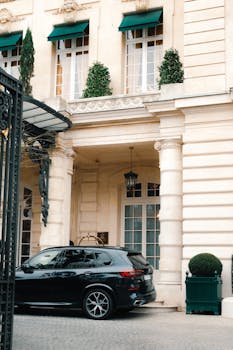 A sleek black car parked outside a grand historic building with architectural columns.