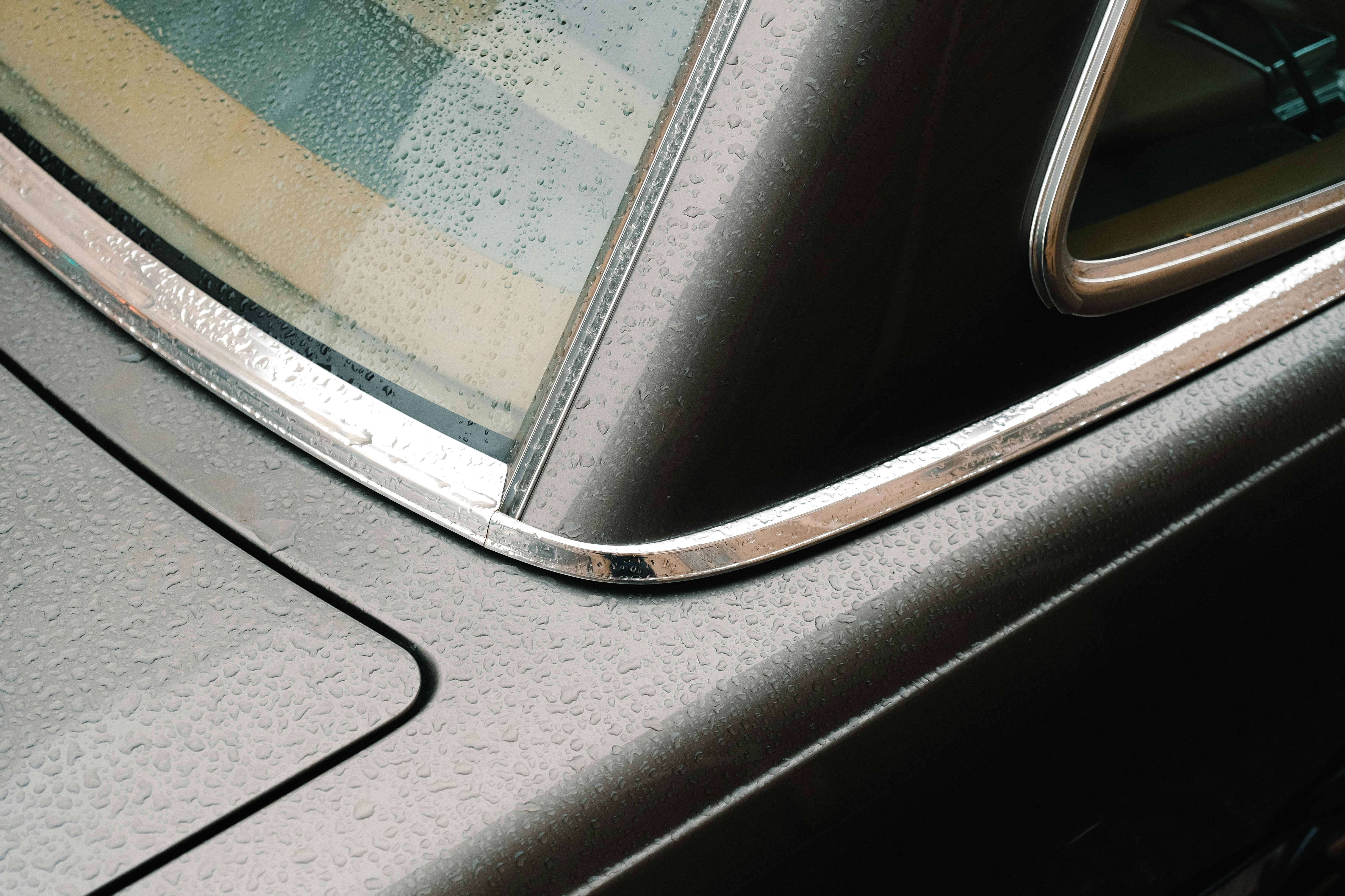 Detailed view of a vintage car's wet surface with raindrops on the window.