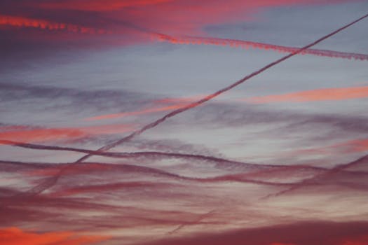Beautiful sunset sky with colorful clouds and visible contrails creating an artistic pattern.