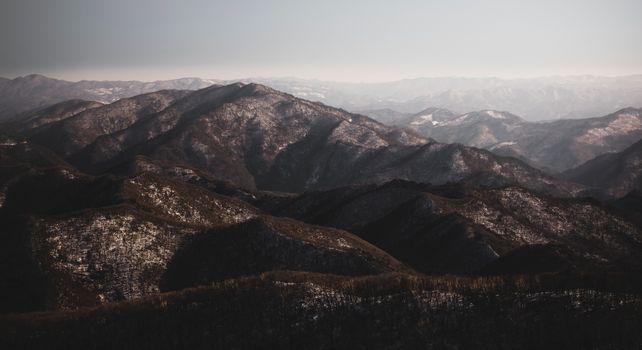 Breathtaking aerial view of Pyeongchang's snow-capped mountains under a clear sky.