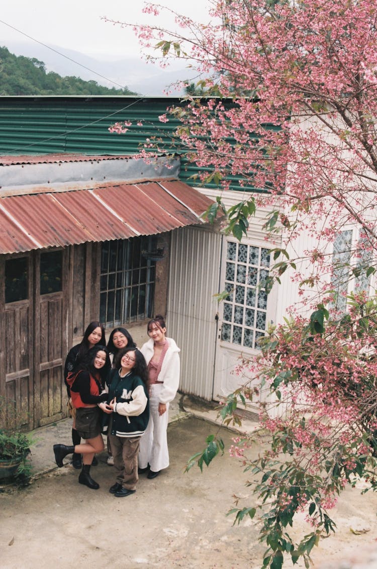 Full Shot Of Women Standing Near A Wooden House 