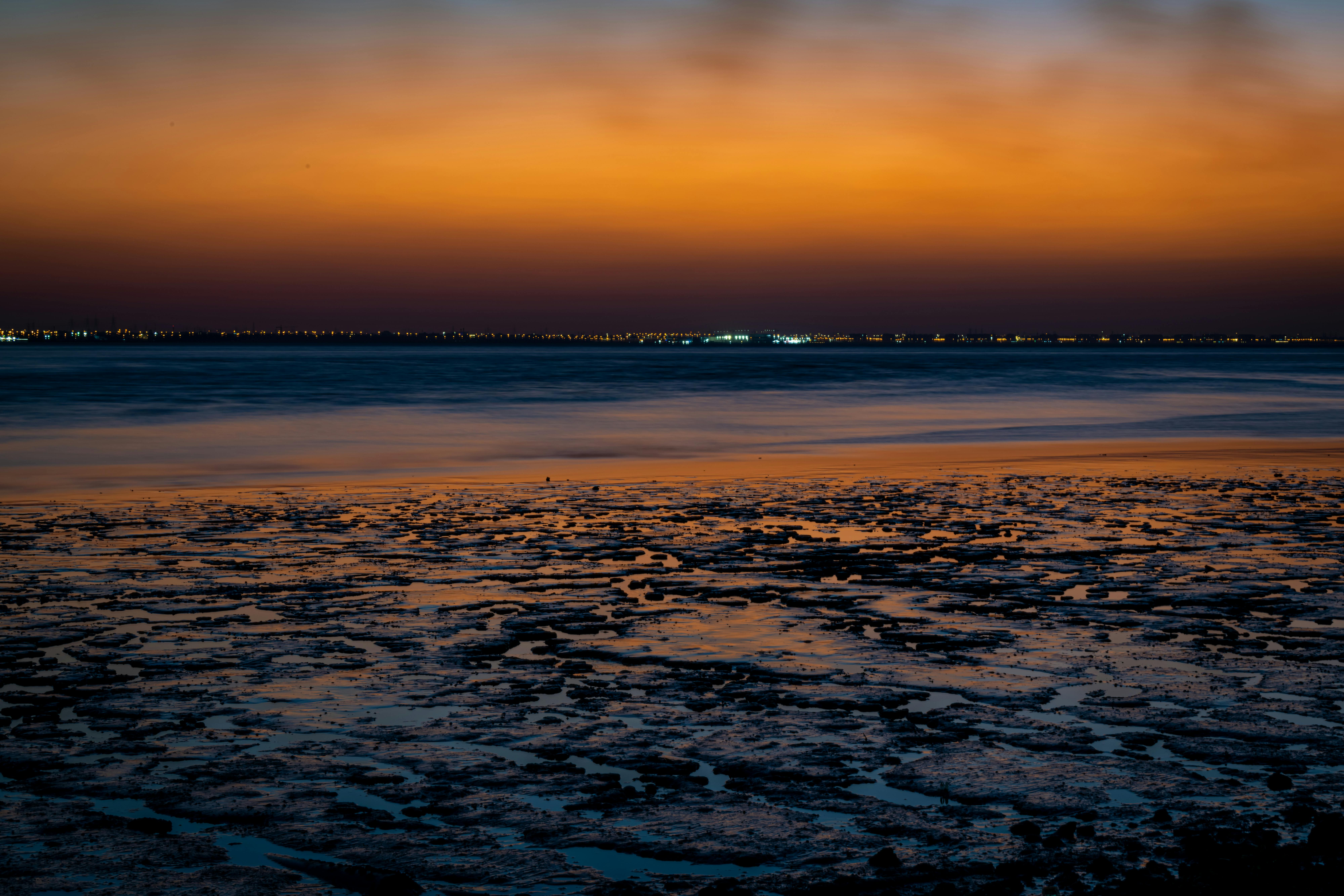 Serene view of Kuwait City's coastline during a vibrant sunset.