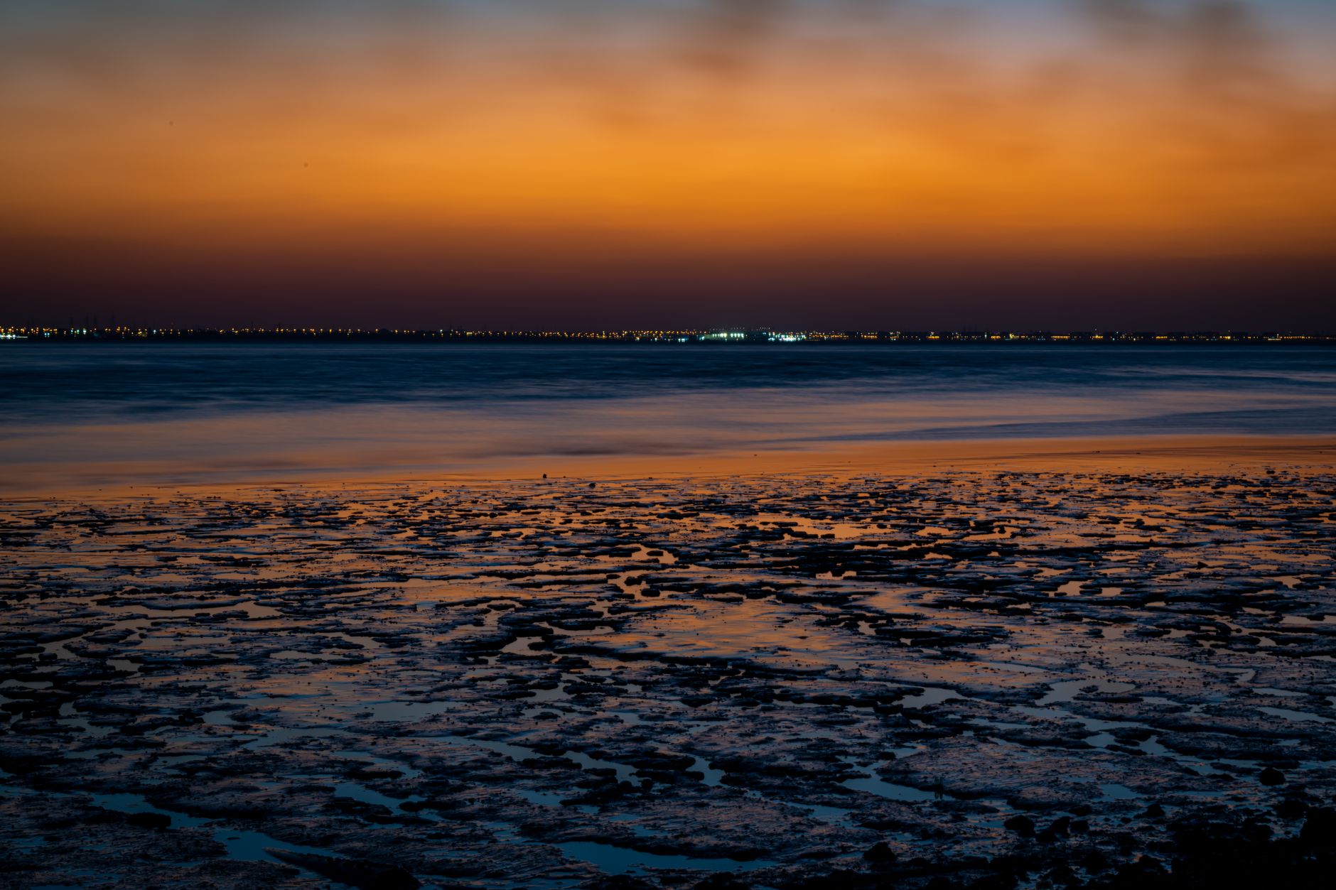 Serene view of Kuwait City's coastline during a vibrant sunset.